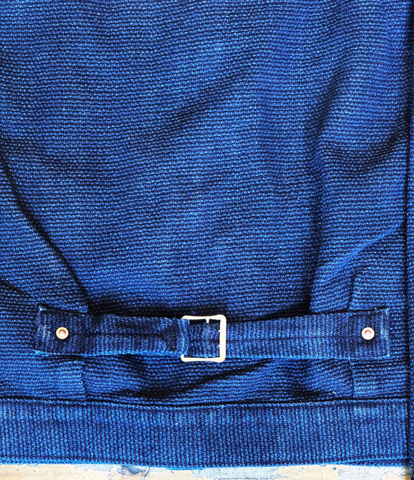 Close-up of a blue fabric with a buckle and buttons on a wooden surface