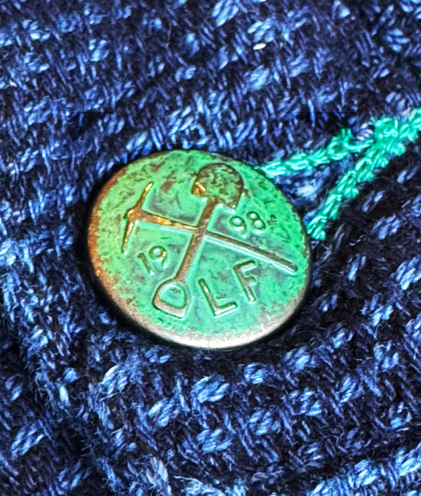 Metallic coin with 'DLF' engraving on a textured blue fabric background