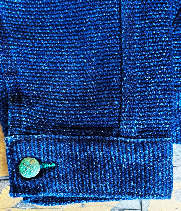 Close-up of a blue textured fabric with a green button on a wooden surface