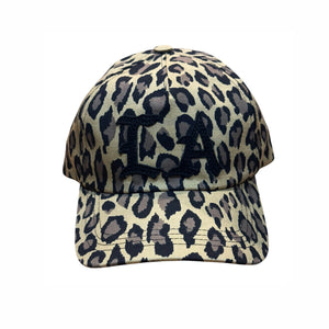 A baseball cap featuring a beige and black leopard print pattern with a black embroidered monogram 'LA' on the front, shown against a plain white background.