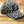 A leopard print baseball cap with a black embroidered letter 'I' on the front, resting on a wooden plank surface.