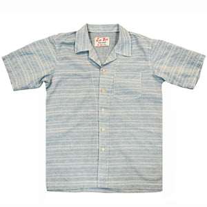 A pale blue short-sleeved camp shirt with Trocus pearl buttons and a collar, displayed against a white background.