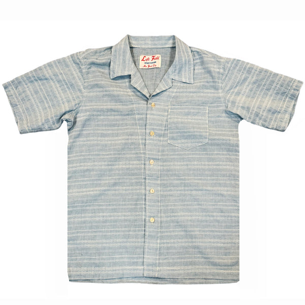 A pale blue short-sleeved camp shirt with Trocus pearl buttons and a collar, displayed against a white background.