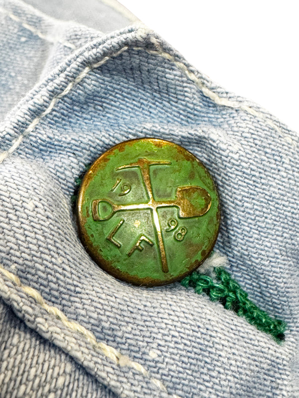 Vintage green button with a logo on a denim background