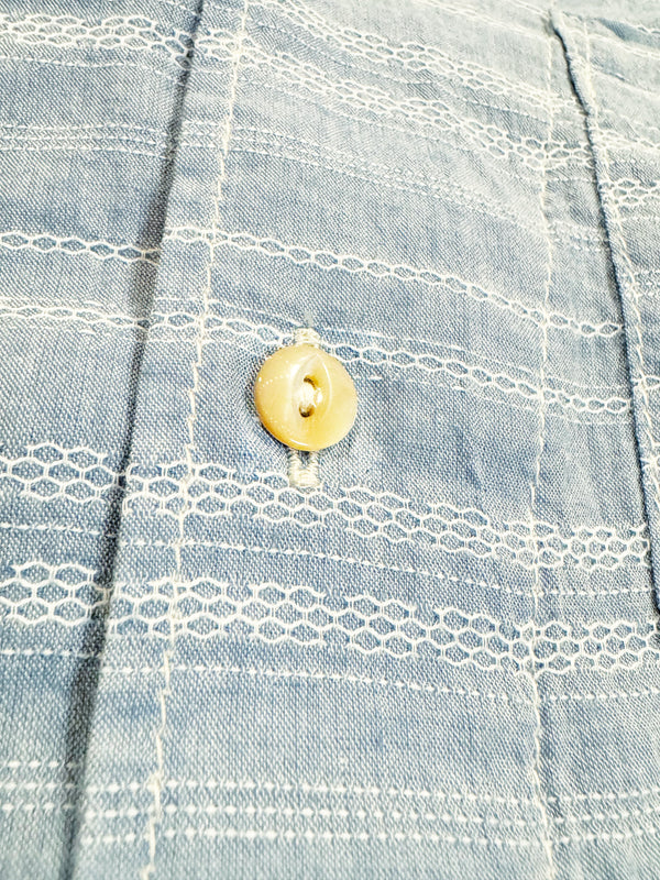 A pale blue short-sleeved camp shirt with Trocus pearl buttons and a collar, displayed against a white background.