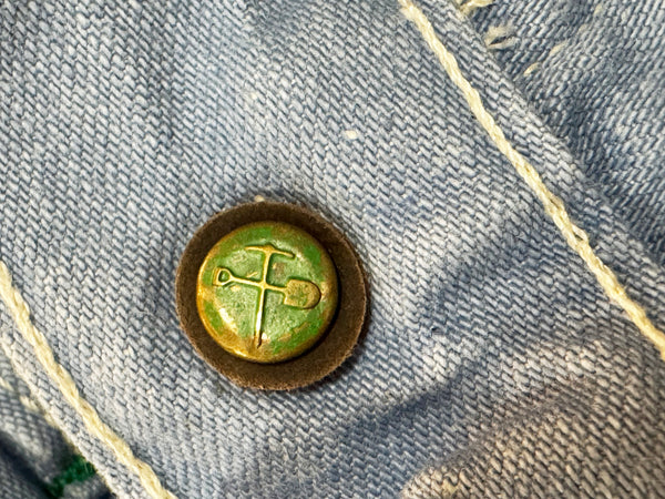 Green button with a cross design on denim fabric