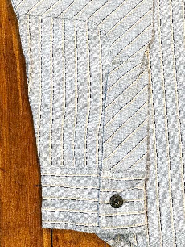 Light blue denim jacket with white pinstripes on a wooden surface