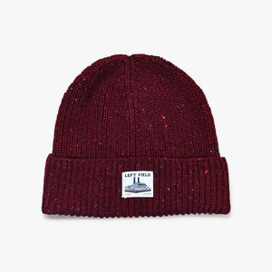 Maroon knit beanie with a label on a light gray background