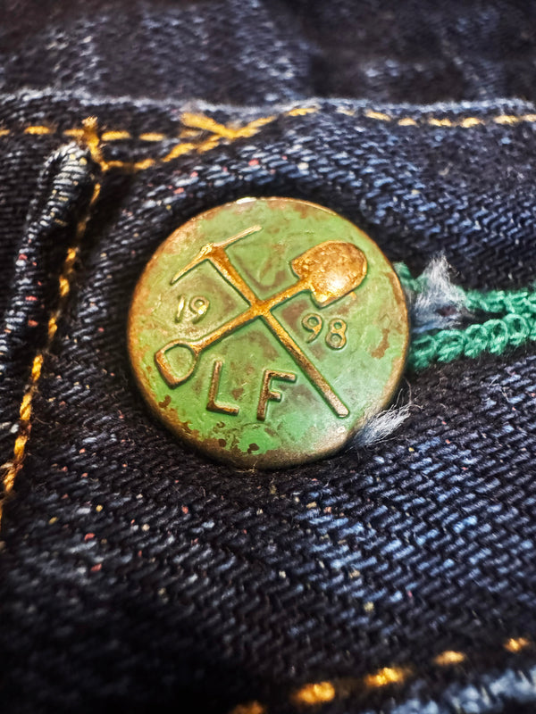 Vintage button with 'DLF' branding on a denim background
