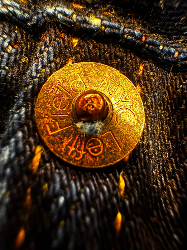 Close-up of a rusted metal button on dark fabric