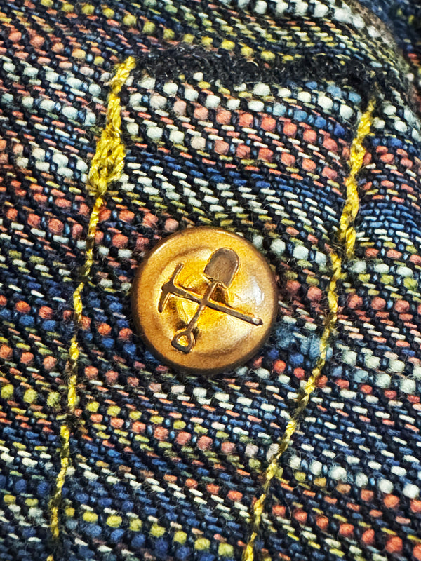 Close-up of a gold button with a design on a textured fabric background