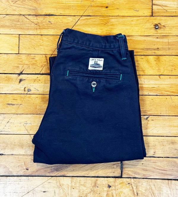 Folded navy blue pants with a brand label on a wooden floor.