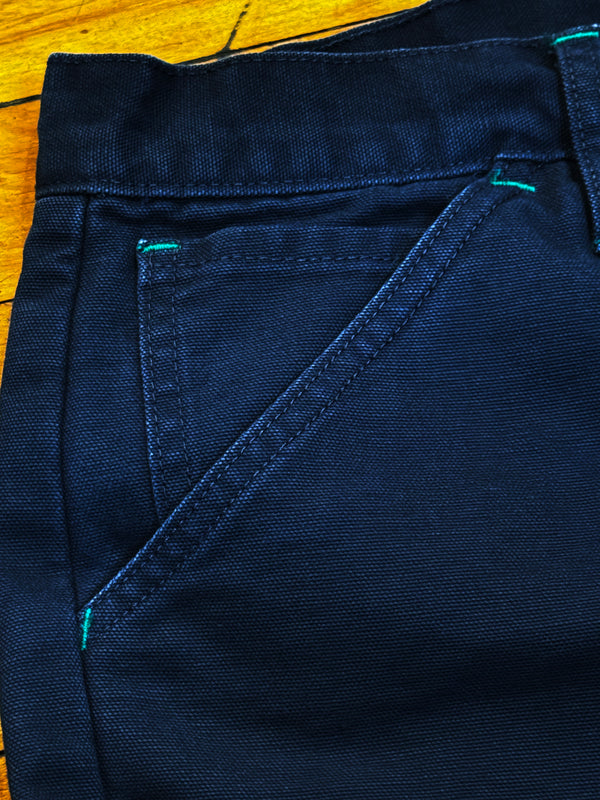 Close-up of dark blue fabric with visible stitching on a wooden surface