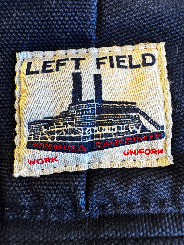 Embroidered label on a dark fabric background with 'LEFT FIELD' branding.