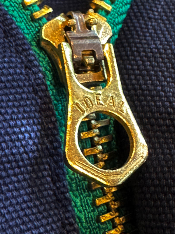 Close-up of a gold zipper pull on green fabric