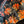 Close-up of a fabric with orange and gold paisley pattern on a dark background