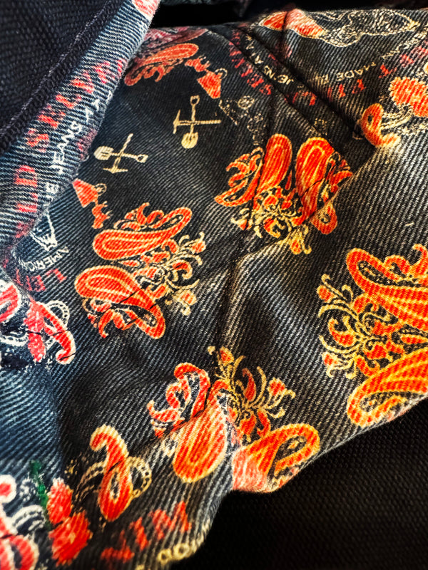 Close-up of a fabric with orange and gold paisley pattern on a dark background