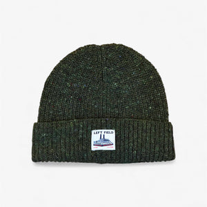 Green knit beanie with a label on a light gray background