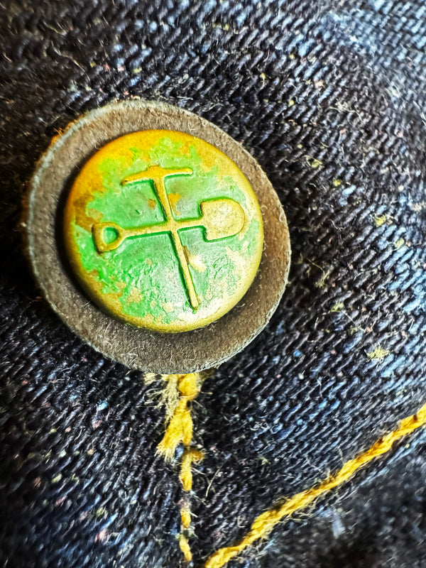 Close-up of a button with a green design on dark fabric