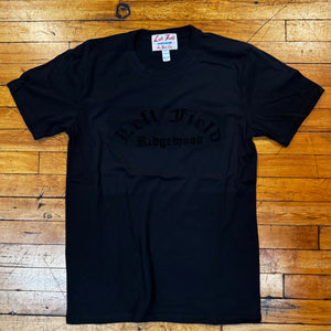 Black t-shirt with text on a wooden floor