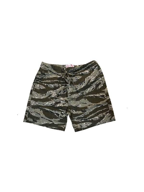 A pair of tiger stripe camouflage shorts in olive green, brown, and black, laid flat against a white background.