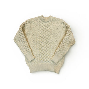 Beige cable knit sweater on a white background
