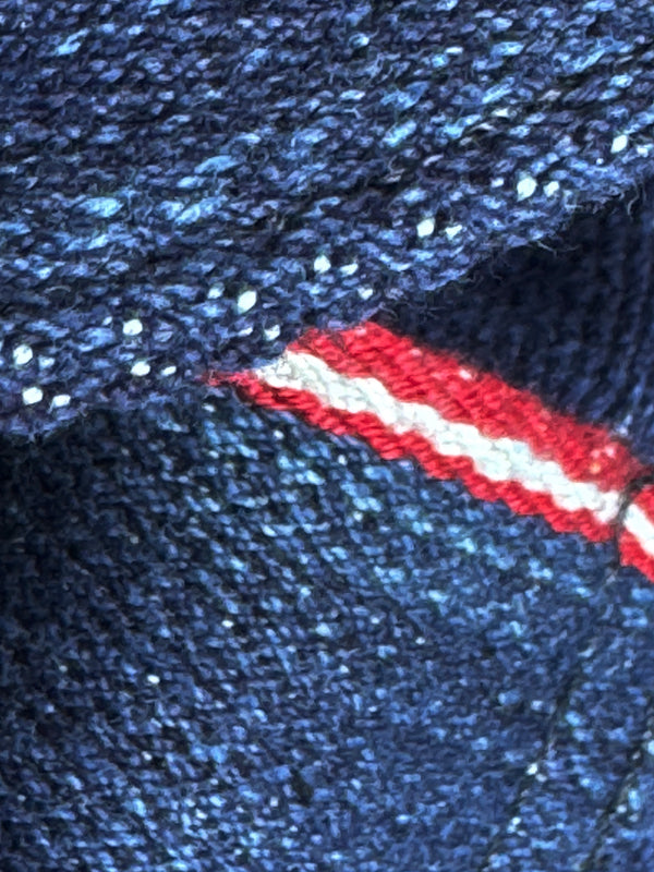 Close-up of a blue textured fabric with a red and white stripe.