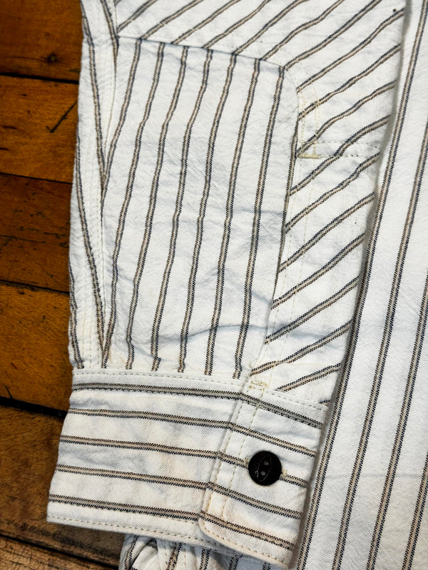 Close-up of a striped shirt with a button on a wooden floor