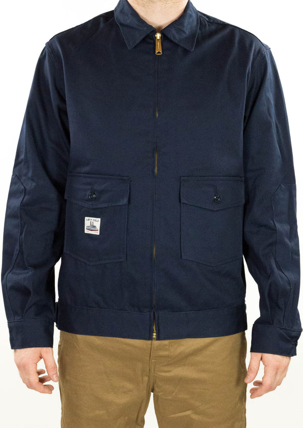 A dark navy garage jacket with a brass zipper and reinforced elbow patches, displayed on a model.